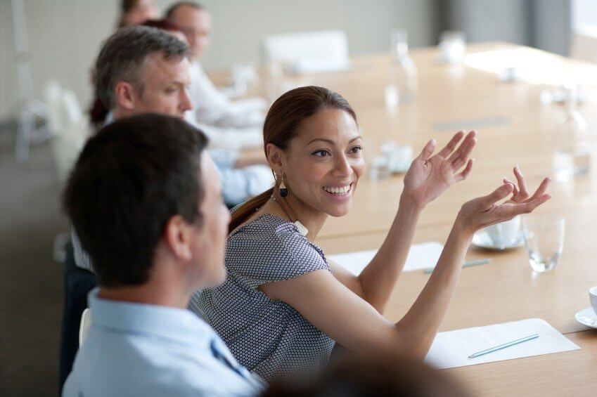 A diverse woman leading a conversation at a boardroom table with young business people