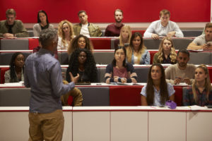Back view of man presenting to students at a lecture