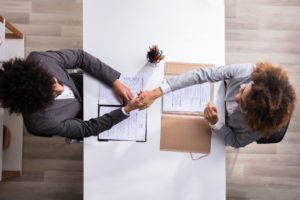 Elevated View Of A Male Manager Shaking Hands With Female Applicant At Workplace