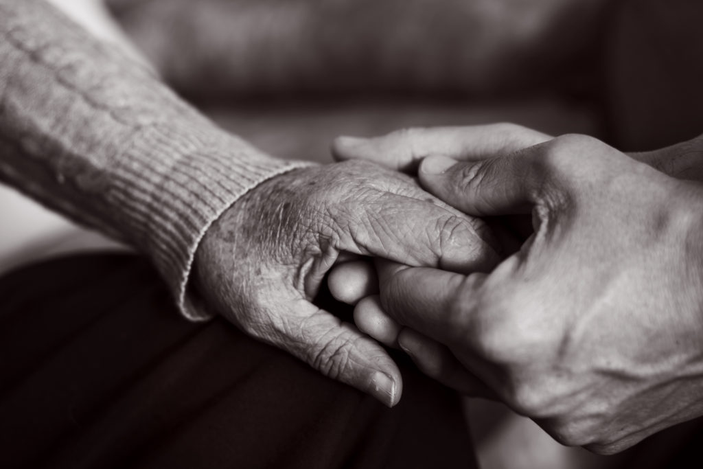 Young man holding the hand of an older women