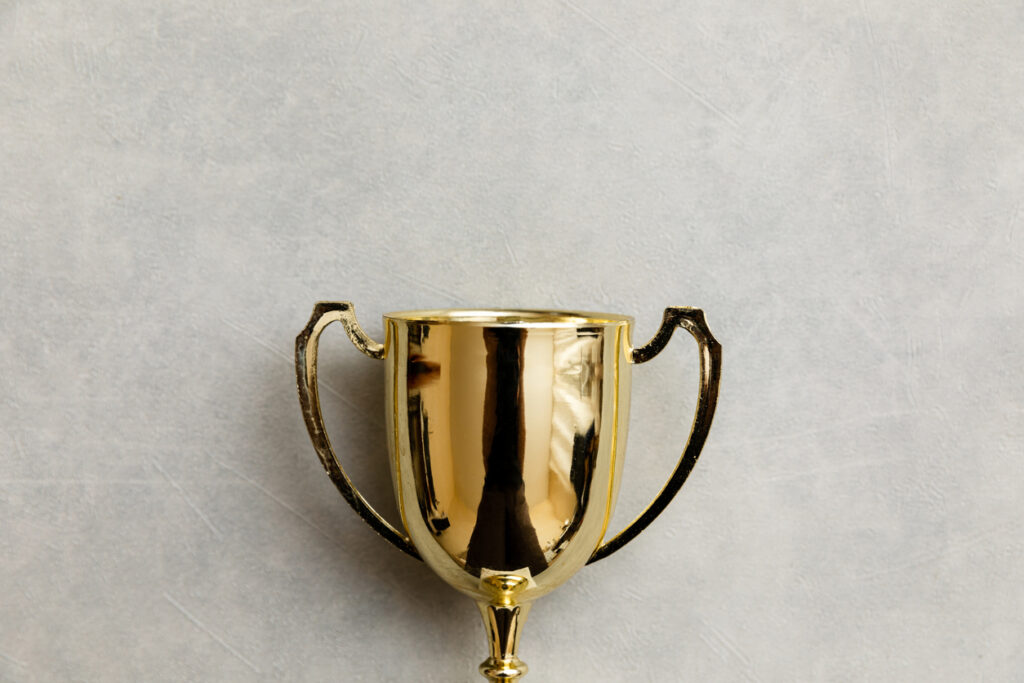 Simply flat lay design winner or champion gold trophy cup on concrete stone grey background. Victory first place of competition. Winning or success concept. Top view copy space Gambrell Professionalism Awards