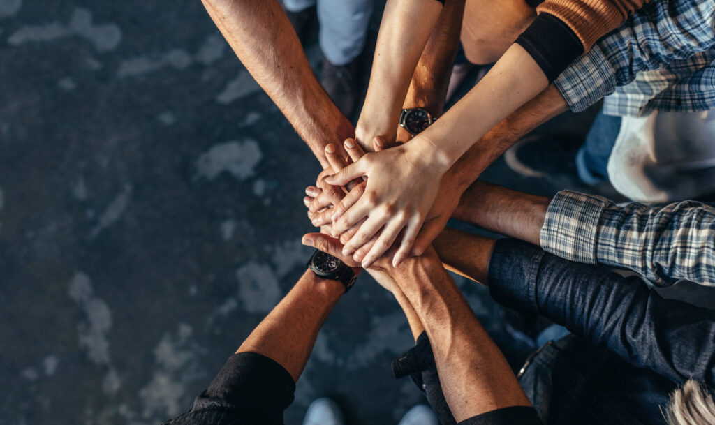 pro bono illinois Top view of creative professionals putting their hands together as a symbol of teamwork, cooperation and unity. Stack of hands of men and woman.