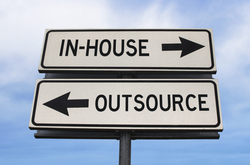 insourcing Outsource versus in-house road sign with two arrows on blue sky background. White two streets sign with arrows on metal pole. Directional sign.